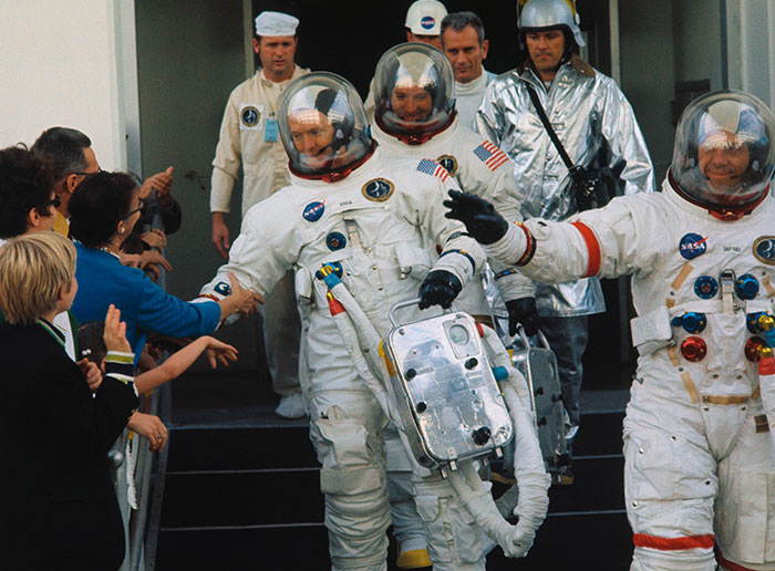 Astronauts in space suits shaking hands with people, related to discussions about NASA photos and alien presence.