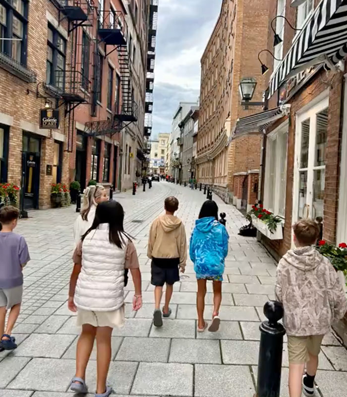Children walking down a narrow, brick-lined street, with old buildings and cloudy skies, relevant to a grieving father. Children walking down a narrow, brick-lined street, with old buildings and cloudy skies, relevant to a grieving father.