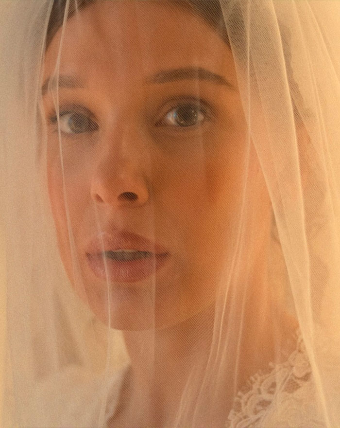 Close-up of Millie Bobby Brown's face partially obscured by a sheer veil, part of the sheer look trend. Close-up of Millie Bobby Brown's face partially obscured by a sheer veil, part of the sheer look trend.