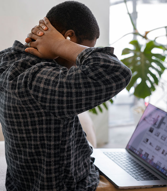 A person stretching their neck while looking at a laptop, illustrating morning habits and health damage from cortisol. A person stretching their neck while looking at a laptop, illustrating morning habits and health damage from cortisol.