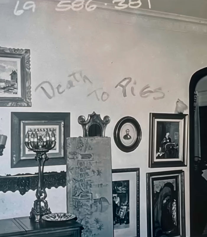 A wall with framed pictures and 'D***h To Pigs' graffitied, hinting at the Charles Manson discovery. A wall with framed pictures and 'D***h To Pigs' graffitied, hinting at the Charles Manson discovery.