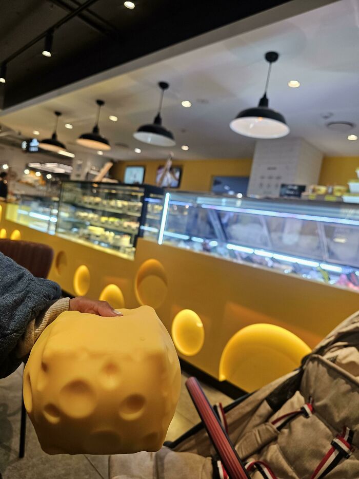 Hand holding a yellow cheese-shaped item that perfectly matches the decor of a shop, an incredibly satisfying paint match.