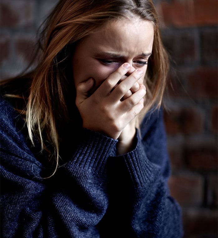 A woman crying with her hand over her mouth, distressed after seeing her husband and sister naked.