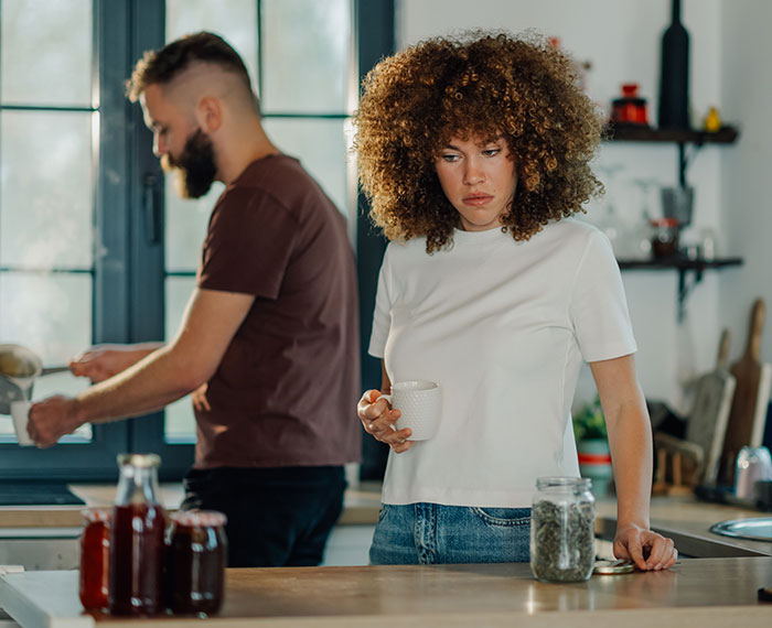 A woman looks distraught with her boyfriend in the background, hinting at relationship issues and revenge. A woman looks distraught with her boyfriend in the background, hinting at relationship issues and revenge.