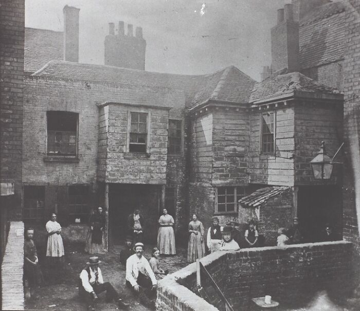 A group of people standing in a courtyard, a curious fact about historical living conditions.
