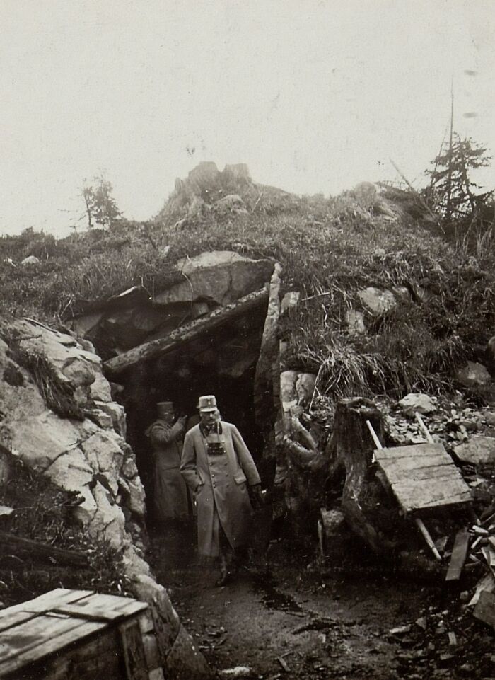 Curious facts about two men exiting a cave entrance in a rocky, overgrown landscape, making you feel smarter with new pics.