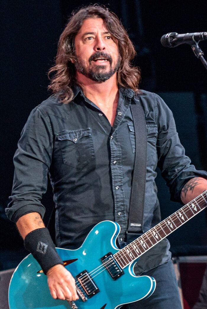 Dave Grohl playing a blue electric guitar on stage, sharing curious facts from his performance.