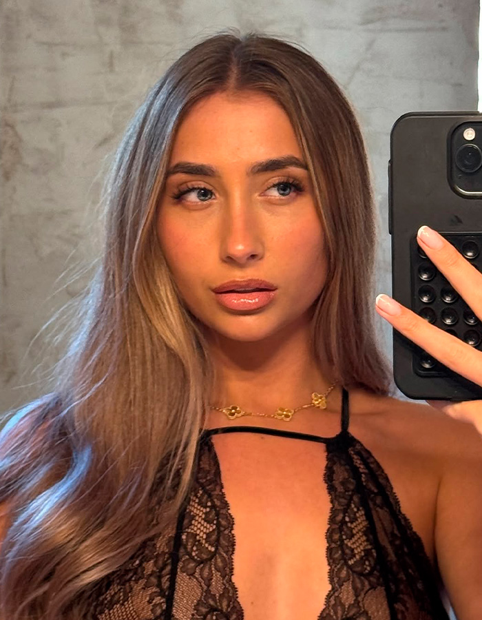 Portrait of a young woman, possibly Lily Phillips, looking surprised while taking a mirror selfie. Portrait of a young woman, possibly Lily Phillips, looking surprised while taking a mirror selfie.