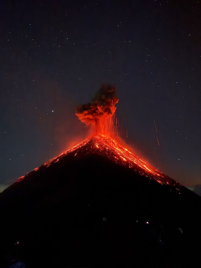 A dramatic night shot of a volcano erupting, with molten lava flowing down, an iPhone Photography Awards winning photo.