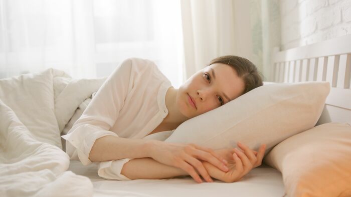 Woman lying in bed looking contemplative, considering if she is overreacting to life-changing scenarios.