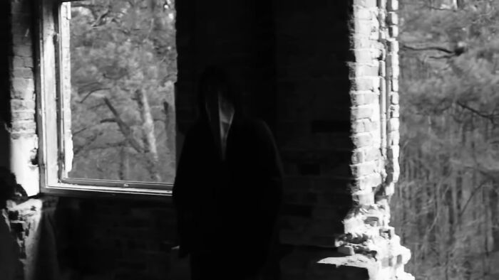 A dark, shadowy figure standing in a dilapidated, abandoned building, symbolizing creepy unsolved mysteries.