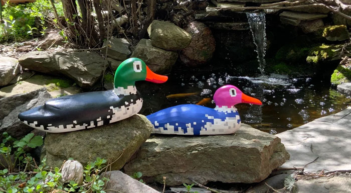 Creative pixelated duck decoys turning old junk into something worth keeping near a pond.