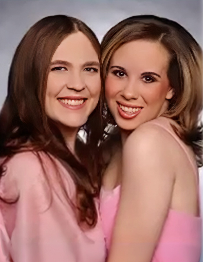 Two smiling young women in pink, a tragic example of sibling disputes gone wrong.