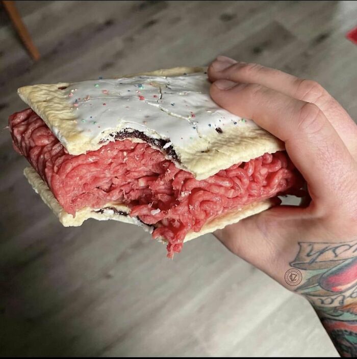 A hand holds a creepy and confusing Poptart filled with raw ground beef, a truly unsettling image.