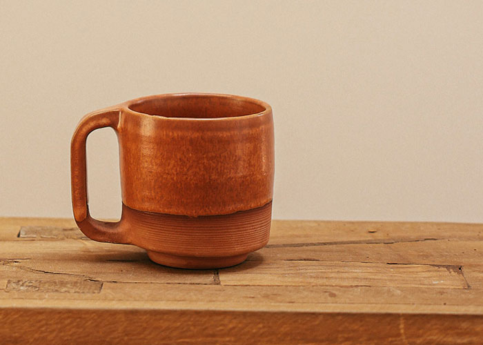 A handcrafted ceramic mug on a wooden table, representing a subtle reality break.