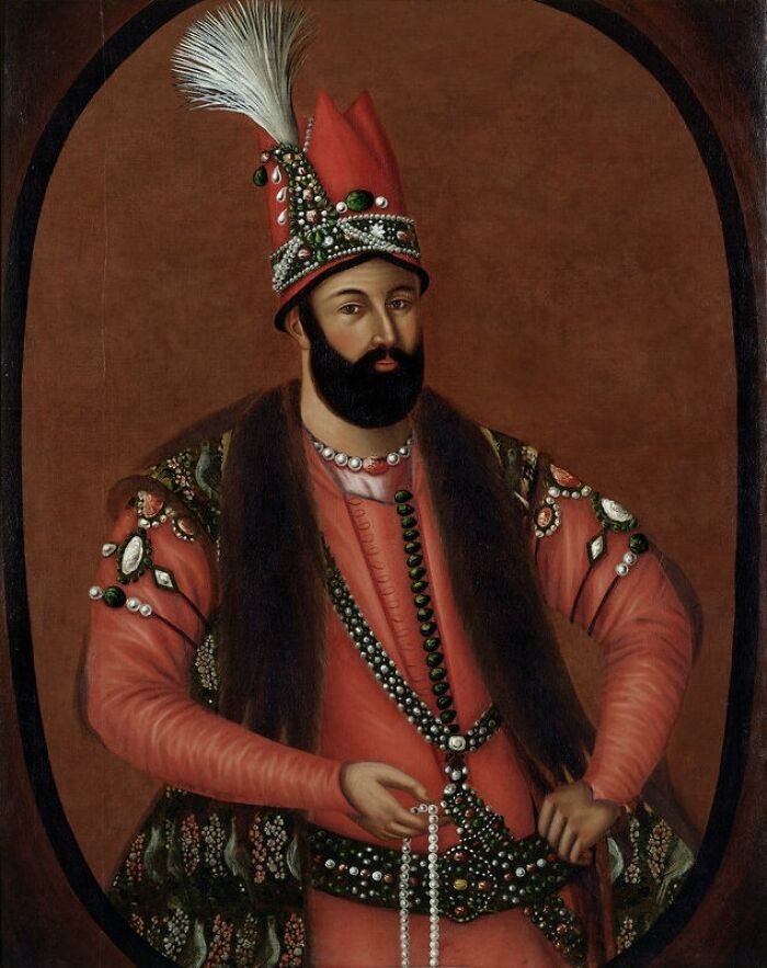 A portrait of a man with a beard, wearing an ornate red hat and jeweled clothing, revealing historical facts.