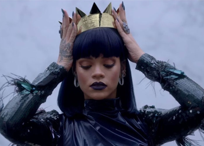 A woman wearing a crown, representing the intimate position called Queening, looking down with dark makeup. A woman wearing a crown, representing the intimate position called Queening, looking down with dark makeup.