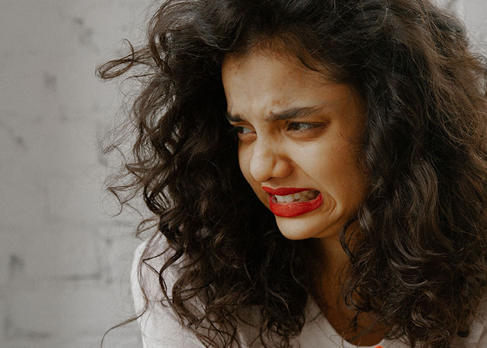 A woman making a disgusted face, possibly at the state of a man's home.