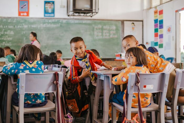 Gen Alpha students in a classroom, with several smiling at the camera and others looking on. Teachers paint a grim picture.