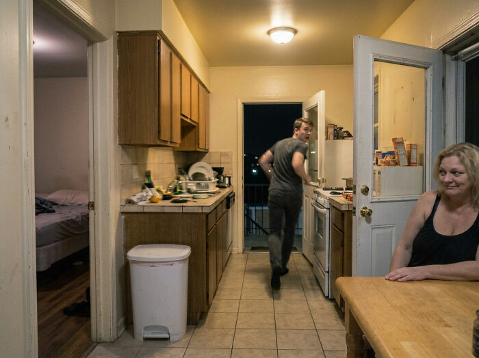 A woman sits at a kitchen table while a man walks away. A moment that makes men freak out in a woman's home.