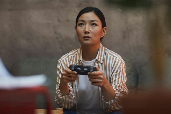 A young Asian woman seriously playing video games with a controller. Men freak out.