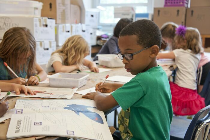 Young Gen Alpha students engaged in an art activity at school, focused on their drawings.