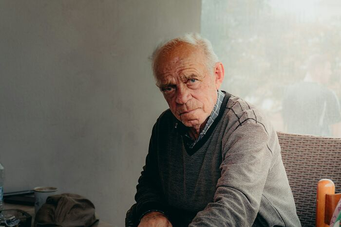 Elderly man with a serious expression, possibly reflecting on deep secrets or depressing memories.