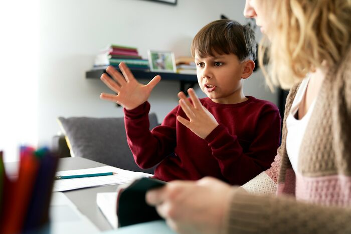 Child expressing strong emotions with hands, potentially sharing messy or deep secrets with an adult.