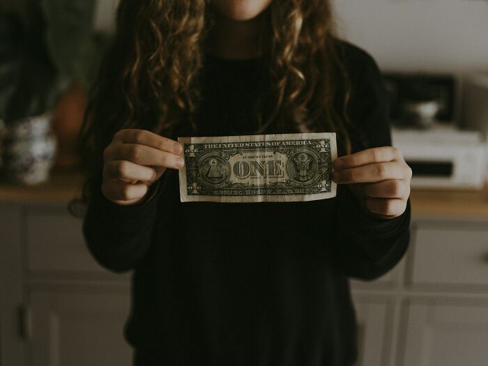 Woman holding a dollar, representing financial deep secrets and struggles.