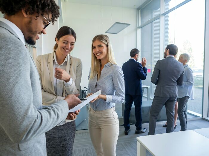Business people smiling and interacting in a modern office, perhaps discussing deep secrets or challenges.