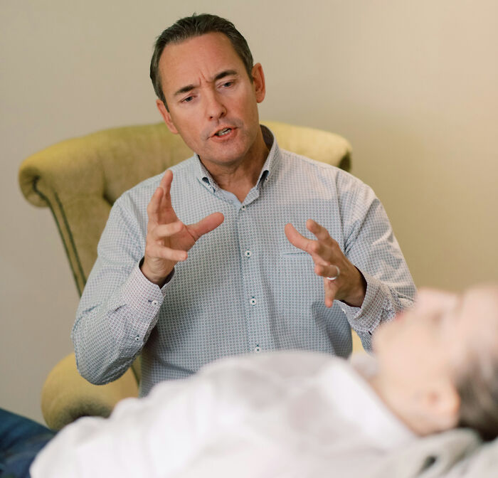 A male therapist gesturing with his hands while speaking to a client, representing unhinged therapist moments.
