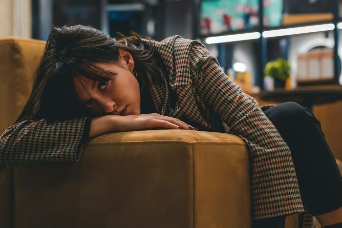 A young woman lies on a couch, appearing depressed and opening up about her secrets.