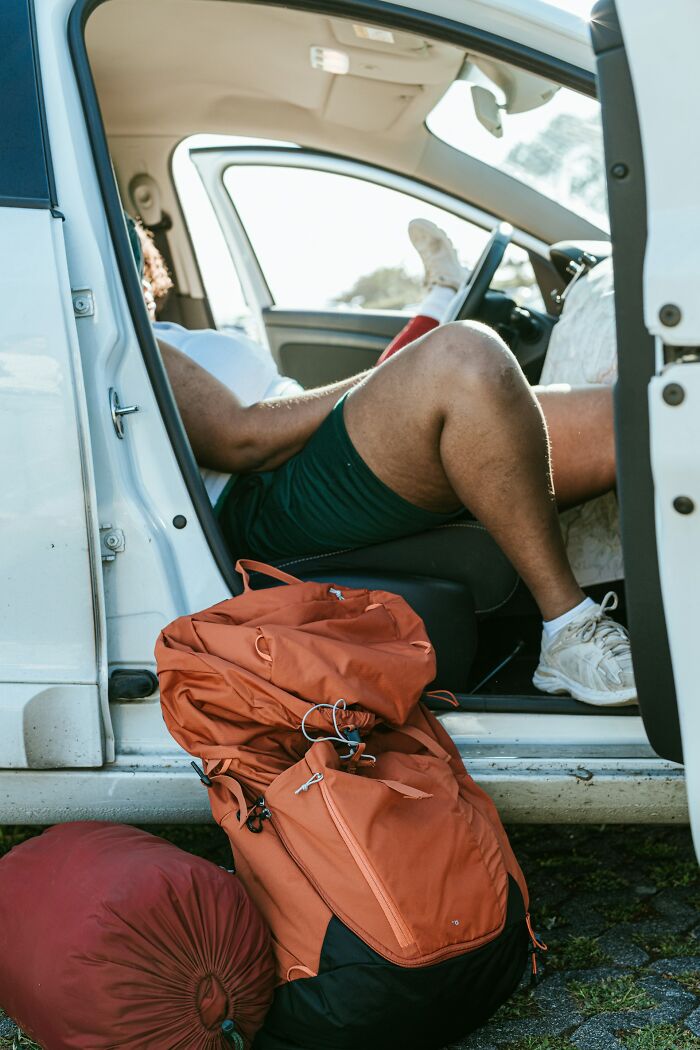 A person with hiking backpacks opens up about their secrets while resting in a car.