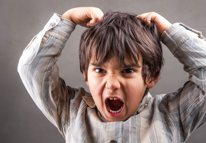 A boy yelling and pulling his hair, a dramatic reaction to something, possibly a clever comeback.