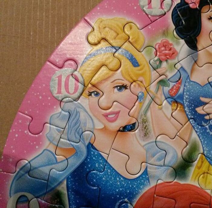 A close-up of a puzzle featuring Disney princesses, with Cinderella's face misaligned due to a designer's mistake.
