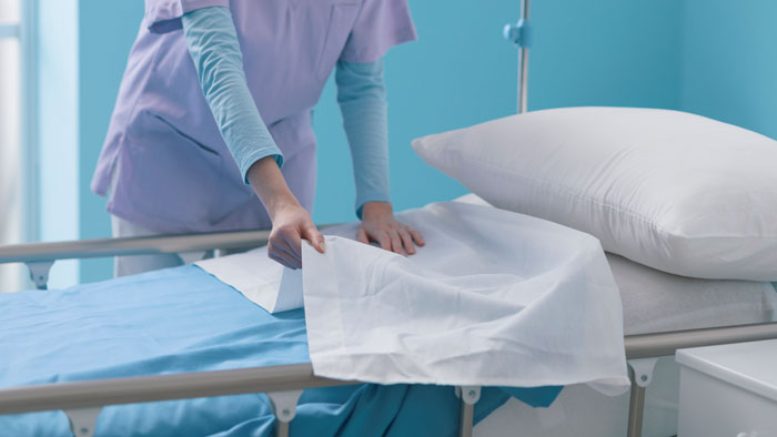 Medical worker changing bedsheets in a hospital room, revealing the hidden side of hospitals.