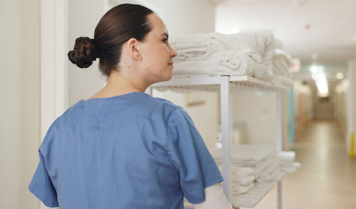 A medical worker pushing a cart of clean linens down a hospital hallway, revealing a hidden side of hospitals.