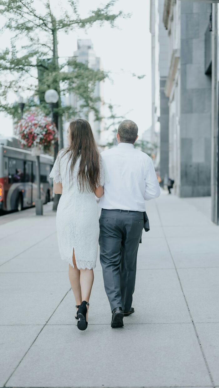 A couple walking away down a city street, depicting an age-gap relationship.