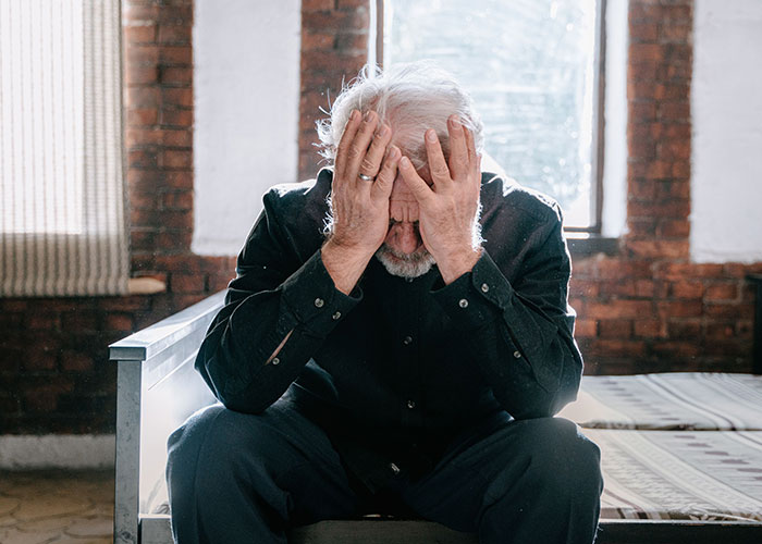 A man with grey hair holding his face, reflecting worry about dementia symptoms. A man with grey hair holding his face, reflecting worry about dementia symptoms.