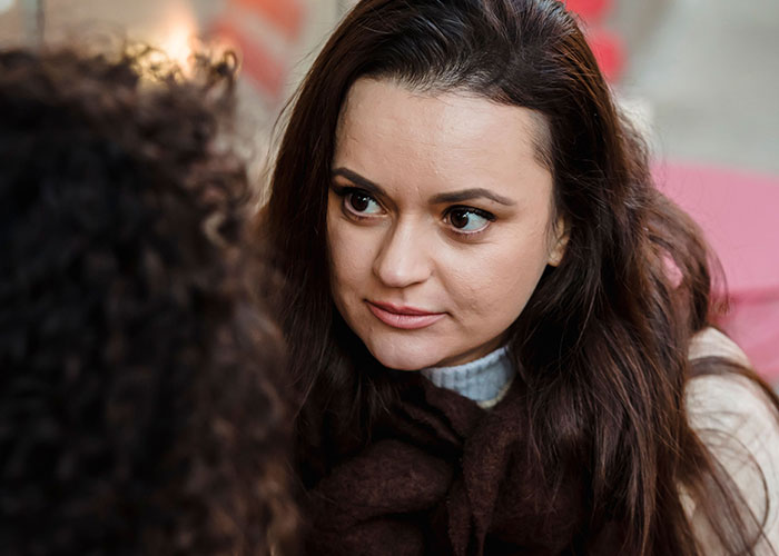 A woman looking intently at another, possibly sharing experiences of reality break.
