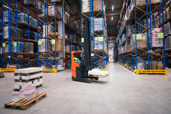 A forklift operating in a large warehouse with many shelves full of products, representing a job scenario.