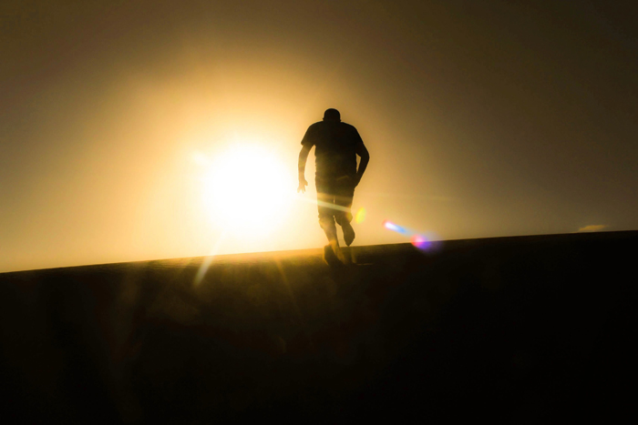 A silhouetted person walking up a hill towards a bright sunset, depicting mysterious things and creepy stories.