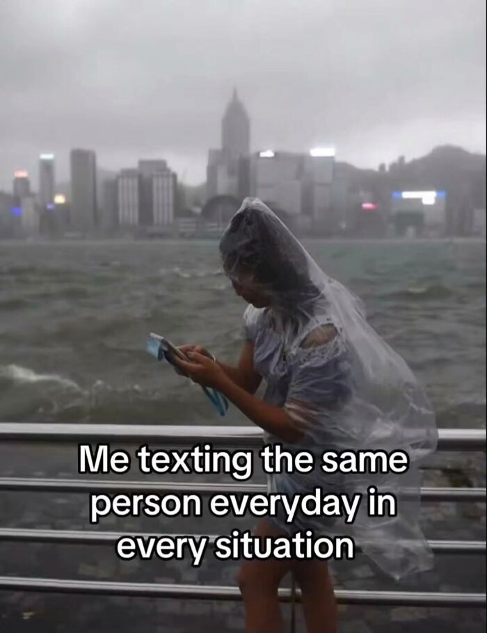 A person in a plastic poncho texting during a storm, representing relatable memes and daily communication.