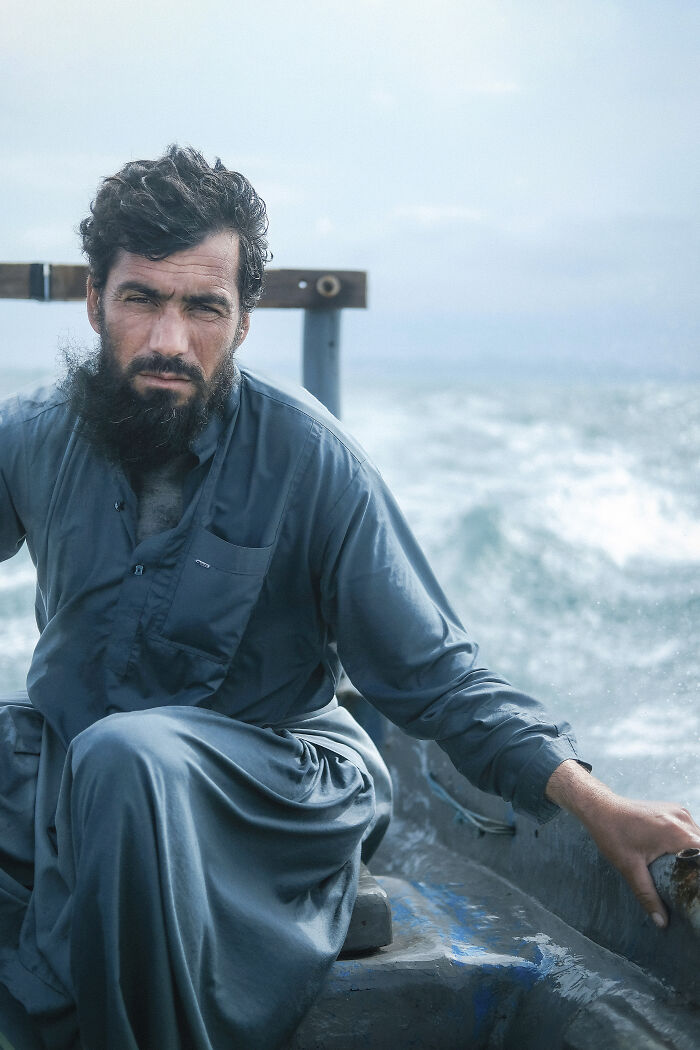 A bearded man in traditional attire on a boat, showcasing the human side of Strait of Hormuz.