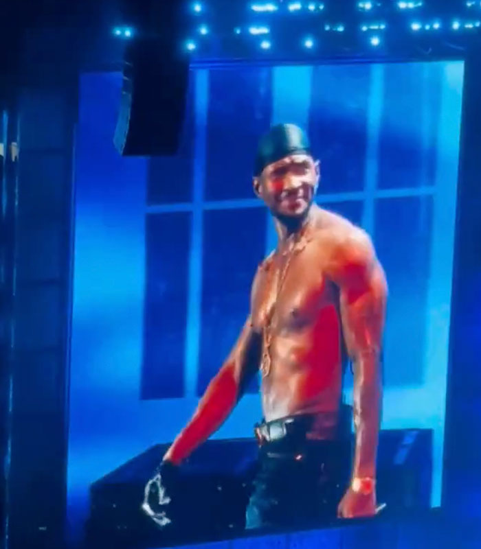 Usher performing on stage, showing his seductive moves that led to a woman's awkward reaction.