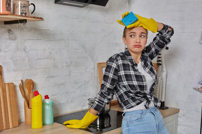 A tired woman in yellow gloves and a sponge on her head. Contact a divorce lawyer for problems beyond cheating.