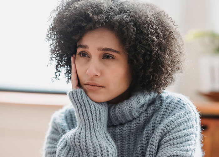 A thoughtful woman resting her face on her hand, feeling the loneliest time. Many reveal why they no longer look forward to their birthdays.