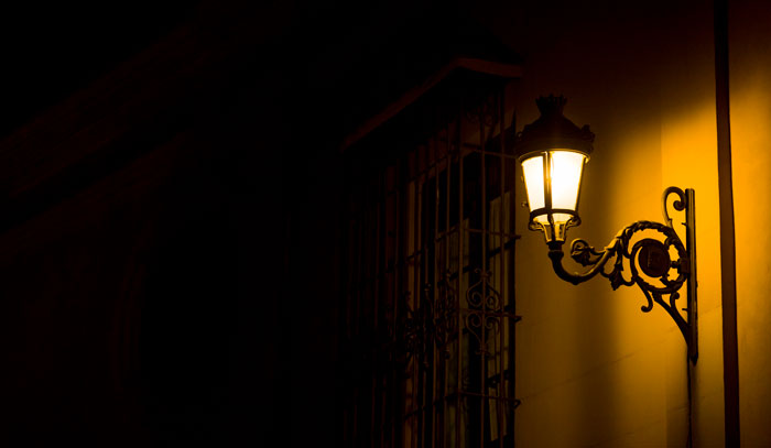 An old-fashioned street lamp casting a warm glow at night, symbolizing hard truths women learned.