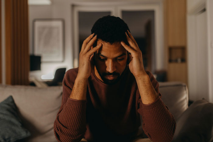 A man looking stressed and holding his head, conveying men's complaints and relationship issues.