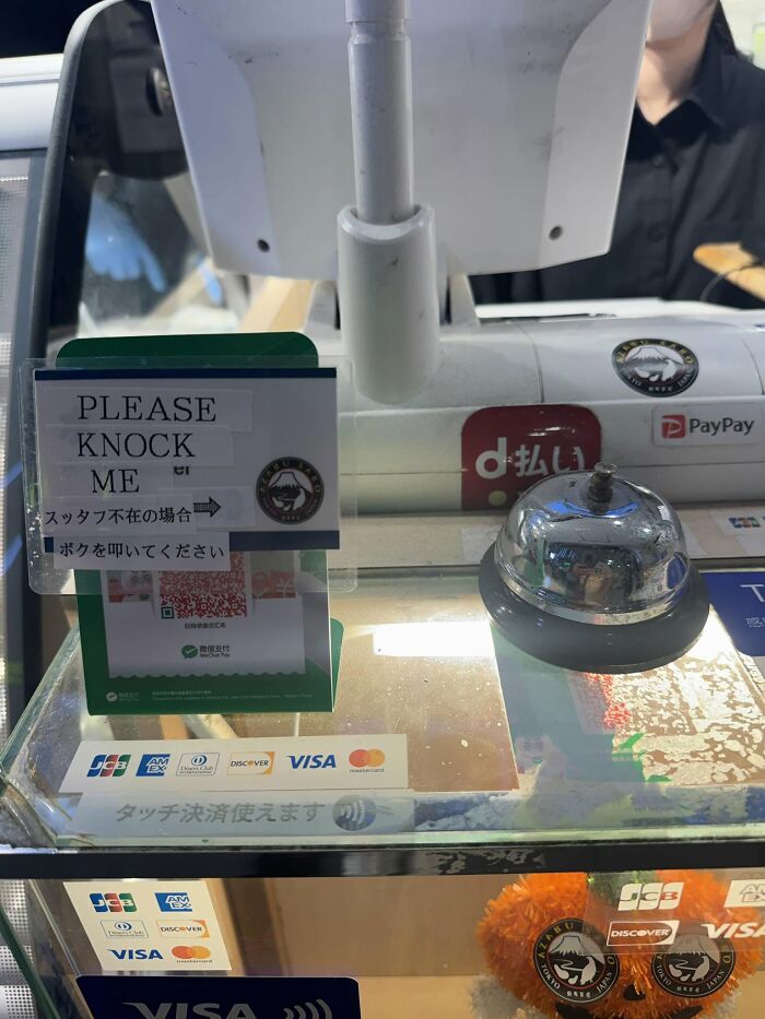 A counter in Japan with a bell and a sign, a hilarious example of getting lost in translation.